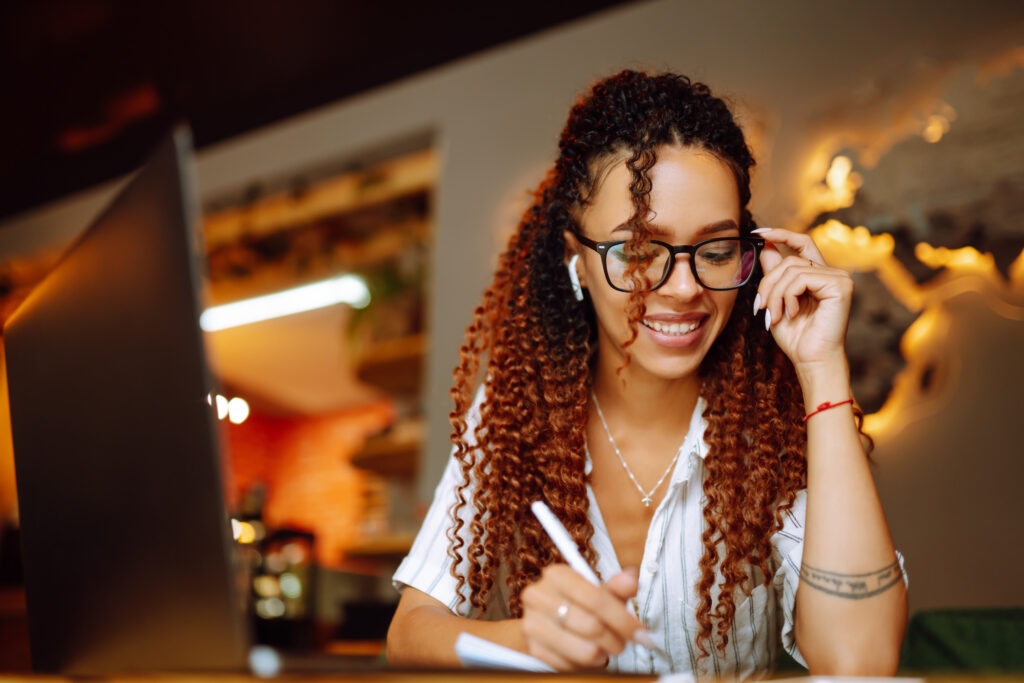 Uma mulhe concentrada e sorrindo para a leitura que está tendo dos artigos da Virtual Sistemas